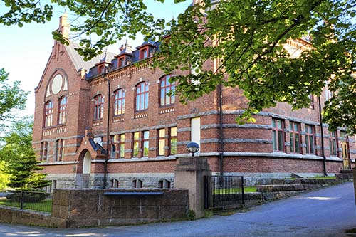 Lahden yhteiskoulun punatiilinen koulurakennus nimeltä Museo kesäisessä maisemassa.