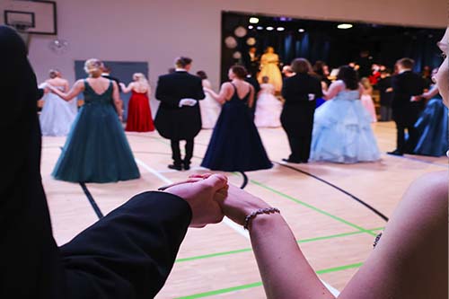 vanhojen-tanssit-kädet Lukion vanhojen tanssit. Tanssipari pitää toisiaan kädestä ja katselee muita tanssipareja vanhojen tansseissa.