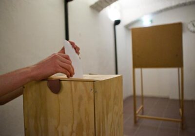 Nuoren henkilön käsi, joka laittaa äänestyslipukkeen uurnaan.