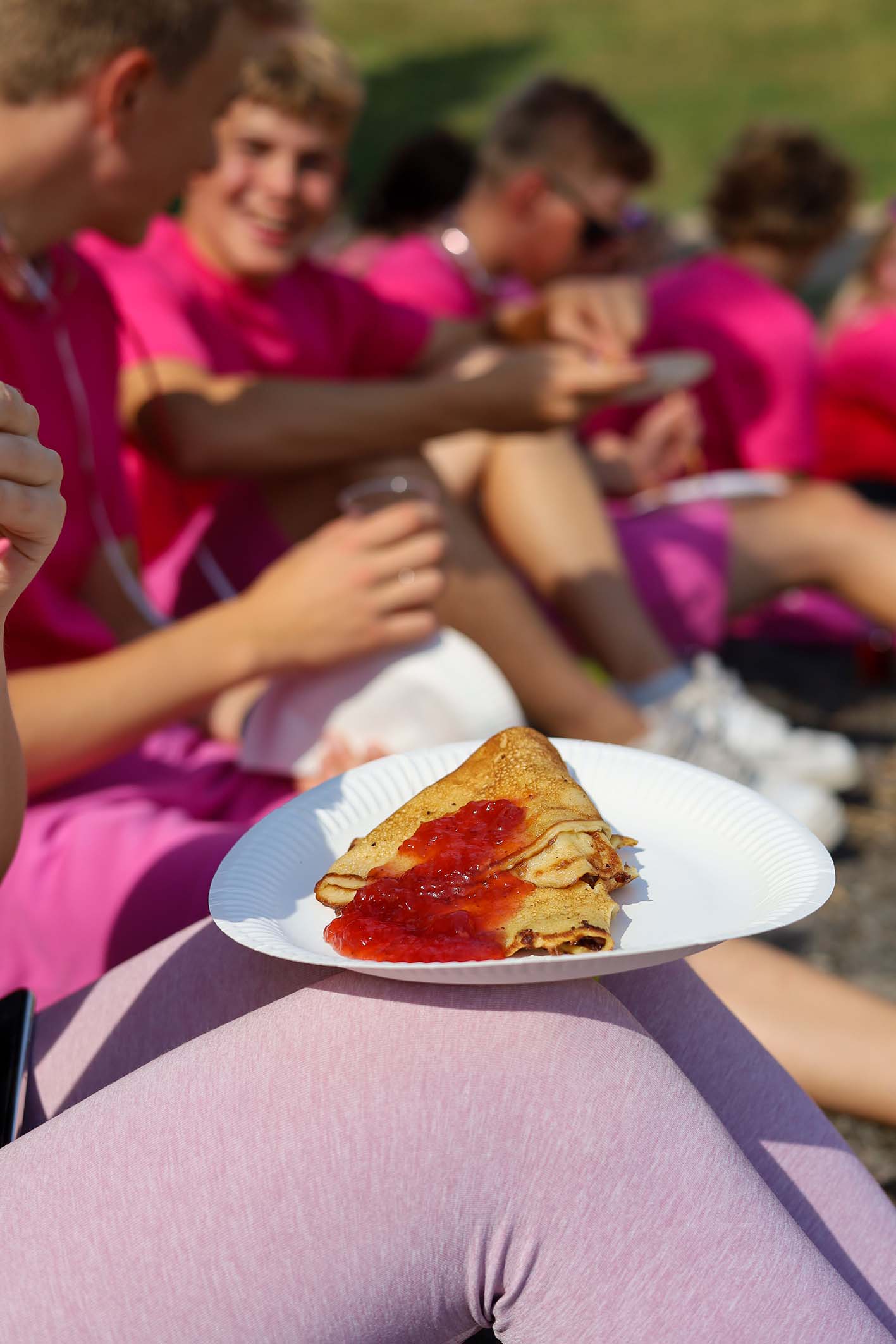 Lettu mansikkahillolla. Lukiolaisia pinkeissä vaatteissa istumassa ja syömässä lettuja.