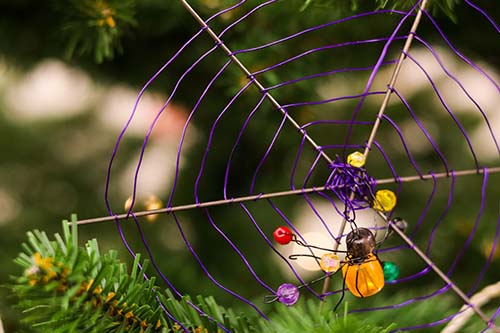 Rautalangasta kudottu hämähäkin verkko ja lasihelmistä tehty hämähäkki joulukuusen koristeina.