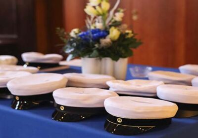 Ylioppilaslakkeja rivissä pöydällä. Keskellä kukka-asetelma.