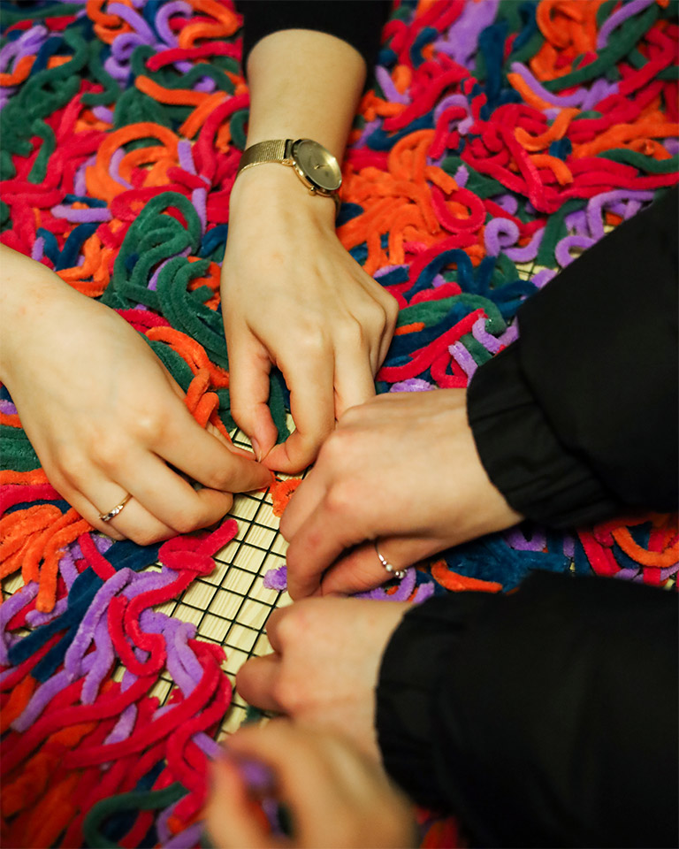 Opiskelijoiden kädet kokoamassa värikästä yhteistaideteosta mielenterveysviikolla Lahden yhteiskoulussa.